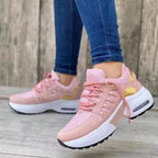 Women's sneakers in pink with gold accents, worn by a person in blue jeans. Fashionable sneakers, ideal for leisure and sport.